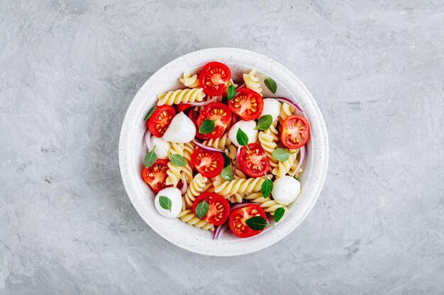 Ensalada de pasta italiana con tomates queso mozzarella cebolla roja y albahaca Espacio de copia de vista superior