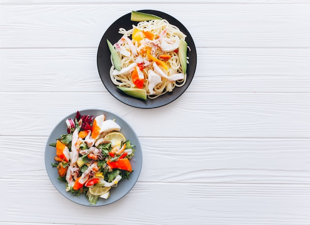 ensalada y pasta con mariscos en el fondo blanco