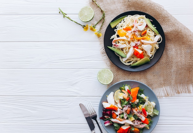 ensalada y pasta con mariscos en el fondo blanco