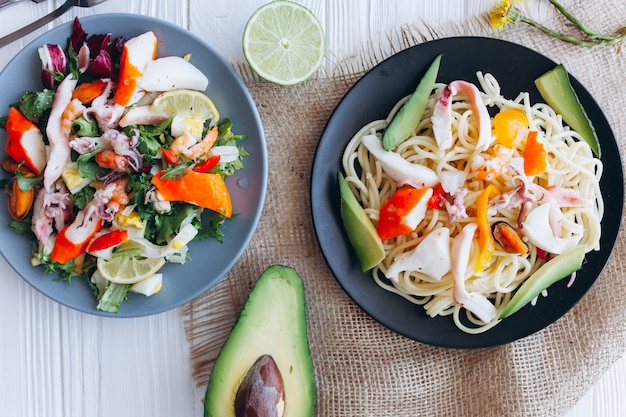 ensalada y pasta con mariscos en el fondo blanco