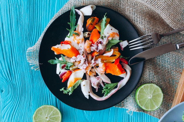 ensalada y pasta con mariscos sobre un fondo azul