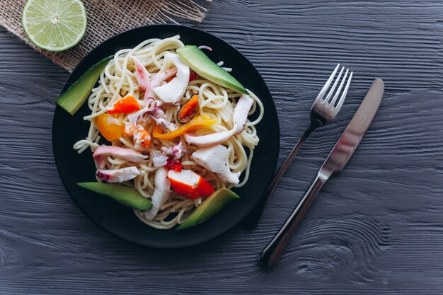 Foto ensalada y pasta con mariscos sobre fondo de madera