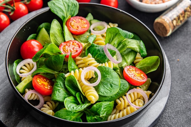 Ensalada de pasta, tomate, pepino, ensalada mixta de hojas verdes, comida saludable Fusilli, refrigerio en la mesa