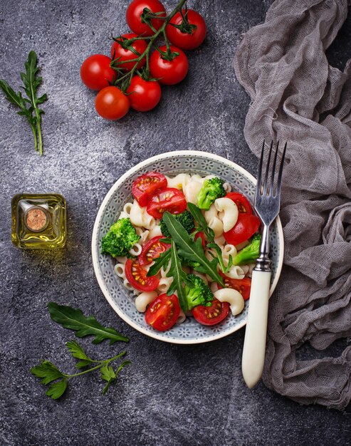 Ensalada con pasta, tomates cherry, brócoli y rúcula. Comida vegana