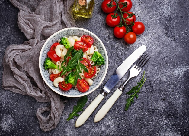 Ensalada con pasta, tomates cherry, brócoli y rúcula. Comida vegana