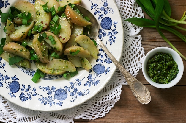 Ensalada de patata vegetariana con ajo salvaje y salsa de pesto sobre un fondo de madera. Estilo rústico