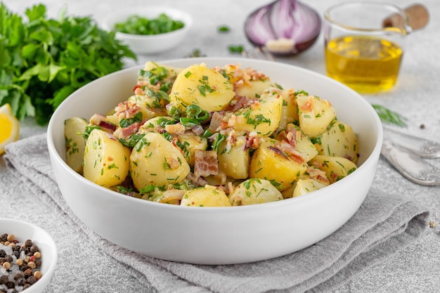 Foto ensalada de patatas calientes con tocino, cebolla, hierbas frescas y vinagre en un cuenco salada de patatas alemana