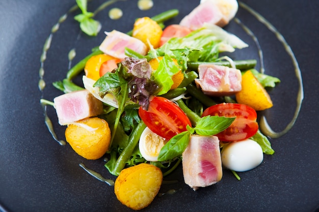 Ensalada de patatas fritas con atún, tomates y salsa.