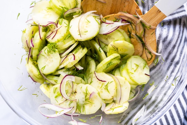 Ensalada de pepino fresco con pepinos en rodajas, cebolla morada y eneldo fresco en un recipiente de vidrio.