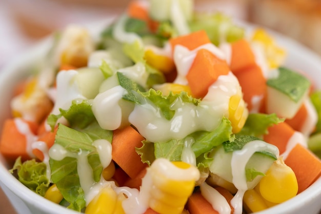 ensalada de pepino zanahoria de maíz y lechuga en una taza blanca