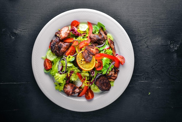 Ensalada con pepinos frescos, tomates y verduras con carne a la parrilla en un plato Tablero de madera Vista superior Espacio libre