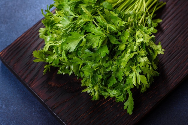 Ensalada de perejil y eneldo en una tabla de cortar oscura contra un fondo de hormigón azul