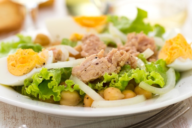 Ensalada de pescado con garbanzos y huevo cocido en plato blanco