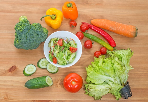 Ensalada picada y verduras frescas enteras en la mesa de madera Vista superior