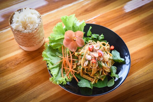 Ensalada picante de brotes de bambú tailandés servido en plato sobre la mesa de madera y arroz ticky sopa seca de brotes de bambú.