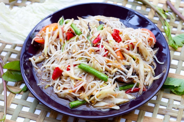 Foto ensalada picante de papaya verde con fideos en blanco