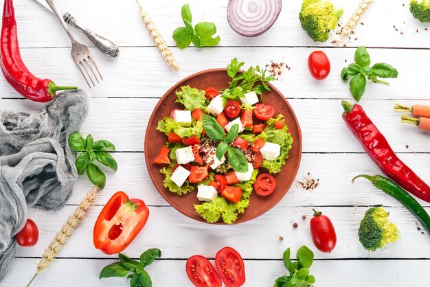 Ensalada en un plato Queso feta Tomates cherry Pimentón Lechuga Comida saludable En una mesa de madera blanca Mesa Vista superior Espacio libre para texto