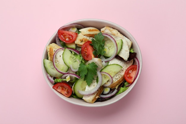 Ensalada de pollo a la plancha sobre fondo rosa