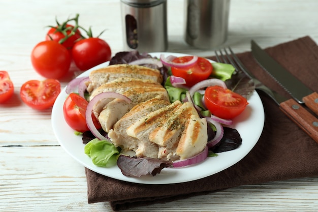 Foto ensalada de pollo a la plancha sobre mesa de madera blanca