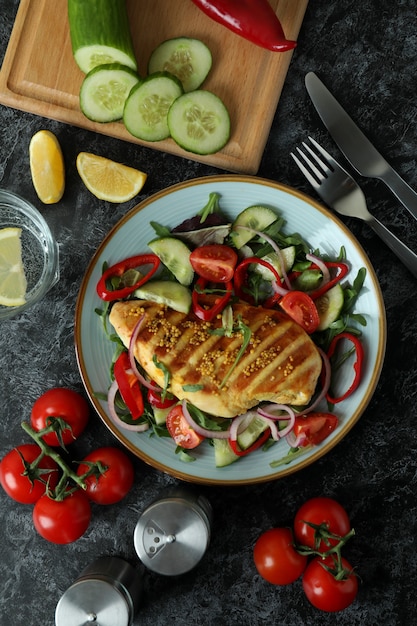 Ensalada de pollo a la plancha sobre mesa con textura negra