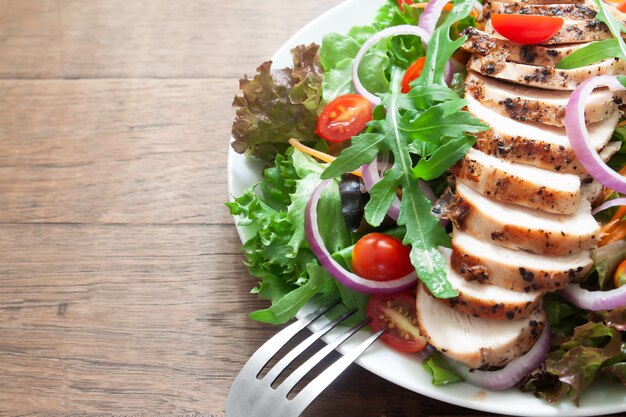 Ensalada de pollo saludable con tomates, cebolla y mezcla de verdes.