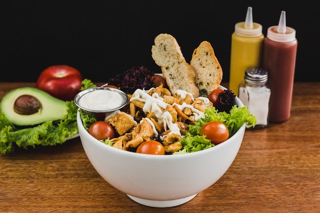 Foto ensalada con pollo teriyaki, lechuga, tomate cherry y salsa de ajo