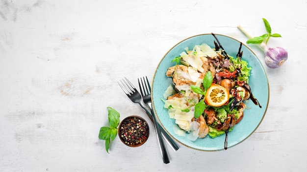 Ensalada con pollo, verduras a la parrilla y queso parmesano En el plato Estilo rústico Vista superior Espacio libre para el texto