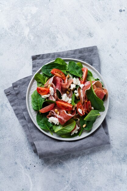 Ensalada de primavera con espinacas, tomate cherry, mozzarella, piñones y jamón