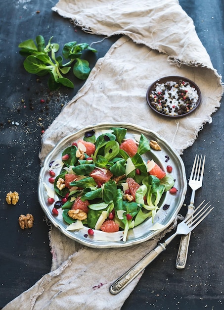 Ensalada de primavera con lechuga de cordero, toronja, granate, nueces en placa de metal vintage