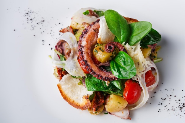 Ensalada de pulpo y verduras de cerca. Apetitosa comida de mariscos frescos del mediterráneo con tostadas, servicio de restaurante