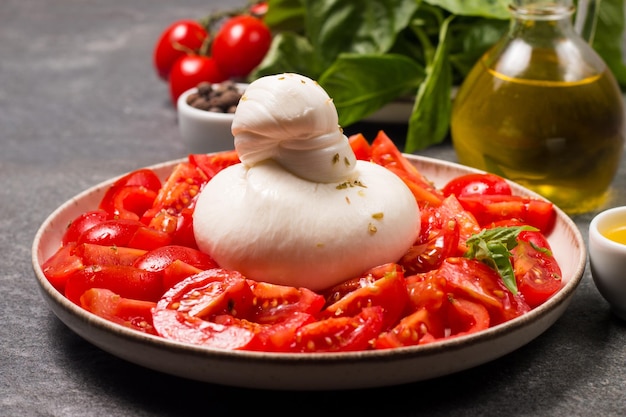 Ensalada de queso burrata con tomates, aceite de oliva y condimentos. Concepto de comida fresca.