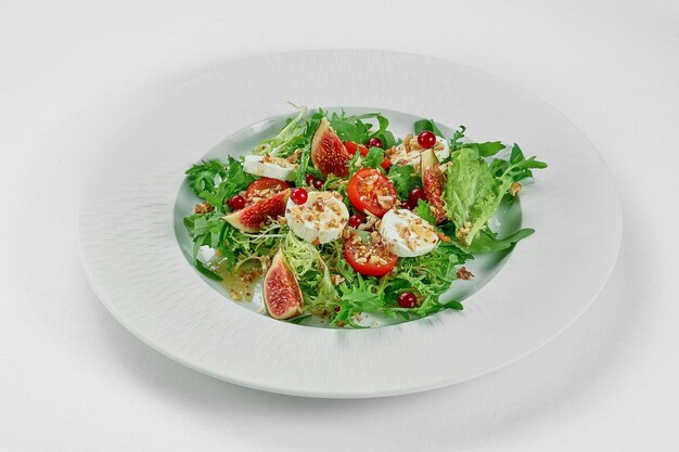 Ensalada con queso de cabra e higos en un plato blanco sobre un mantel blanco Primer enfoque selectivo