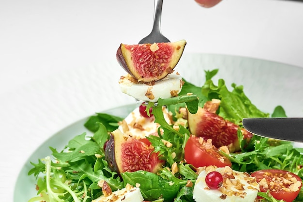 Ensalada con queso de cabra e higos en un plato blanco sobre un mantel blanco Primer enfoque selectivo