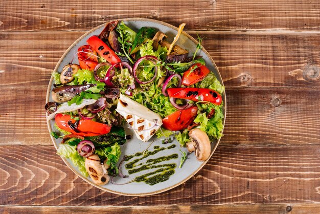 Ensalada con queso, champiñones y verduras sobre fondo de madera