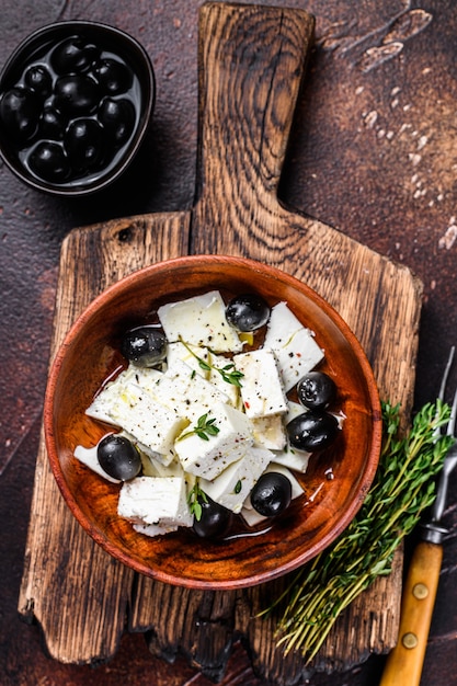 Ensalada con queso feta fresco, tomillo y aceitunas. Fondo oscuro. Vista superior.