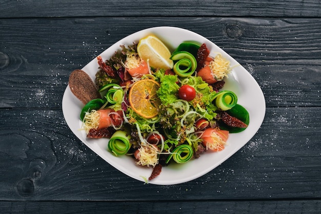 Ensalada con queso de salmón salado y hojas de ensalada Sobre una superficie de madera Vista superior Espacio libre para el texto