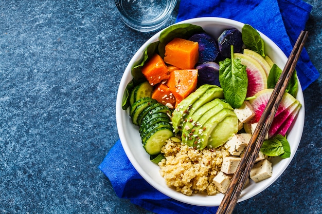 Ensalada de quinoa con tofu, aguacate y vegetales en un tazón blanco