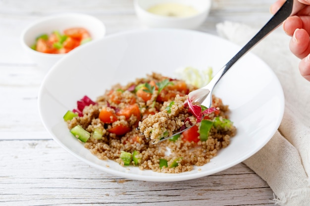 Ensalada de quinua rústica saludable con verduras en una mesa de madera blanca