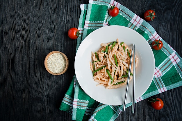 Ensalada con rábano daikon, cebolla verde, miel y chile rojo en polvo. Ensalada asiática Endecha plana. . Oscuro