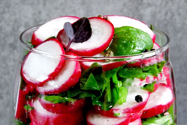 Ensalada de rábano con espinacas en un frasco. Ensalada de fitness en el frasco. Ensalada de verduras en un frasco para llevar.