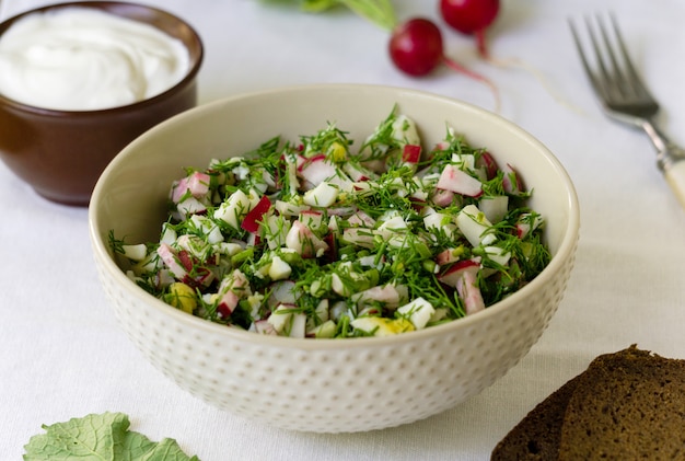 Ensalada con rábano, huevos y eneldo sobre un fondo de tela blanca