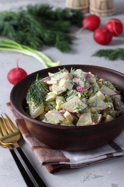 Ensalada de rábanos, cebollas verdes, huevos y eneldo sazonado con crema agria en un cuenco oscuro