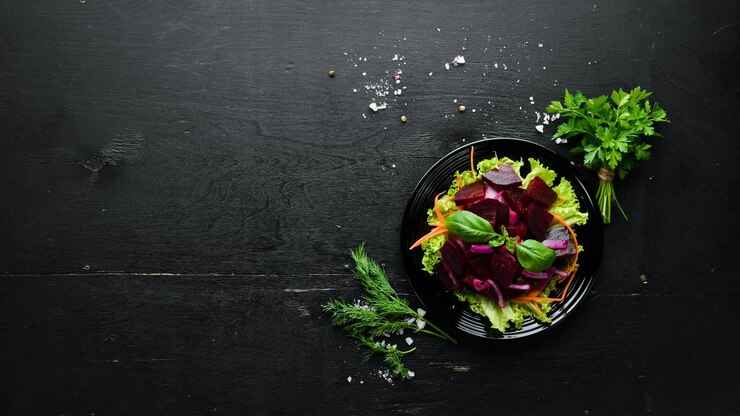 Ensalada de remolacha con cebolla en un plato negro sobre un fondo negro Vista superior Espacio libre para su texto
