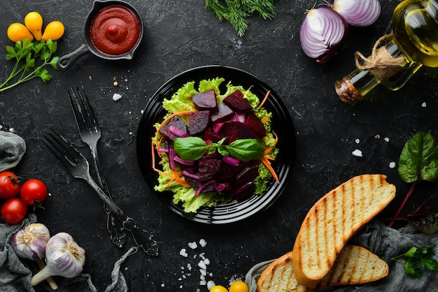 Ensalada de remolacha con cebolla en un plato negro sobre un fondo negro Vista superior Espacio libre para su texto