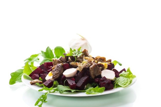 Ensalada con remolacha hervida, berenjenas fritas, hierbas y rúcula en un plato aislado de fondo blanco