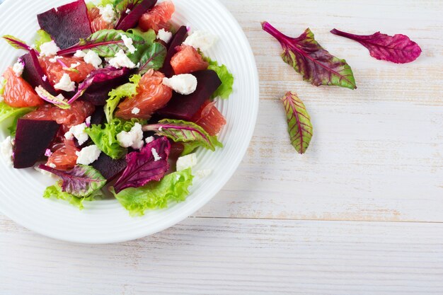 Ensalada de remolacha, lechuga, hojas de remolacha, pomelo y queso feta en una mesa de luz.