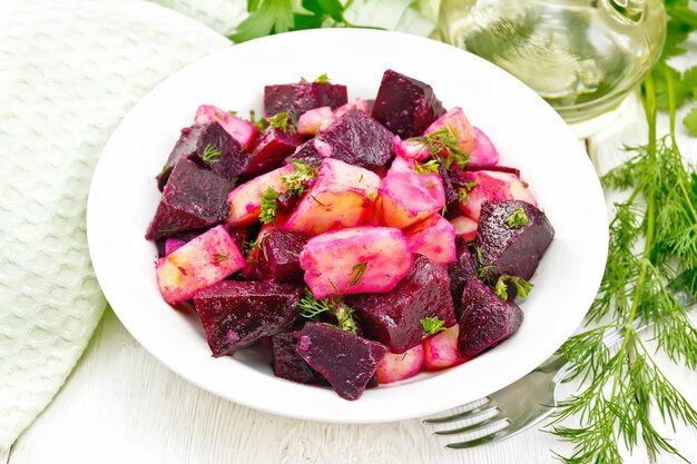 Foto ensalada de remolacha y patatas en plato sobre tabla de madera