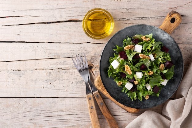 Ensalada de remolacha con queso feta, lechuga y nueces sobre mesa de madera rústica