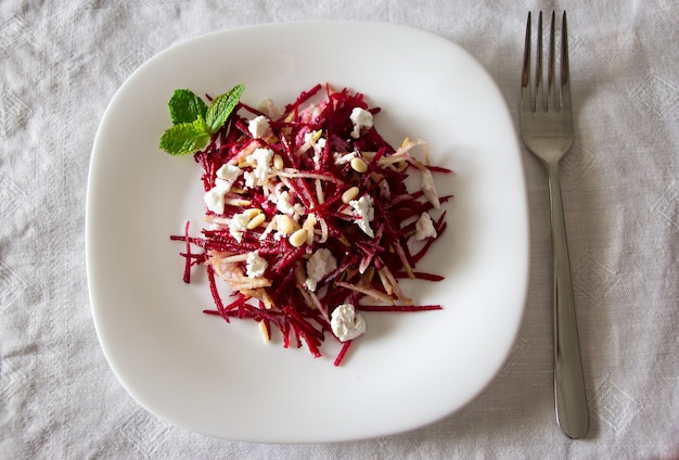 Ensalada de remolacha con queso feta, peras y nueces aliñando aceite de girasol.