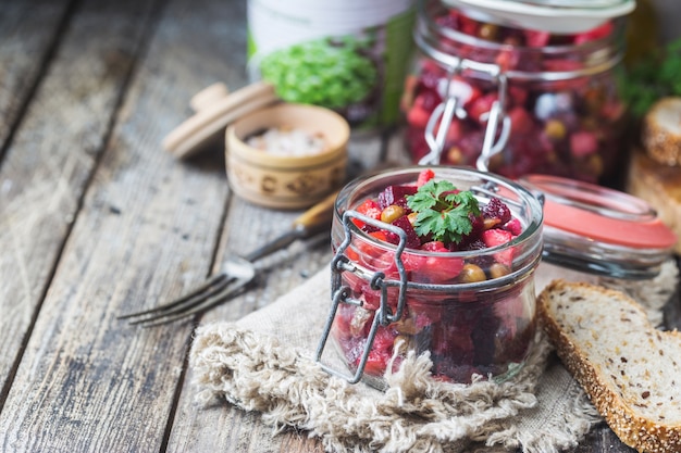 Ensalada de remolacha rusa vinagreta en un frasco de vidrio con pan de centeno, fondo rústico